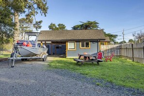 A house with a gravel driveway, a boat trailer, and a picnic table with chairs.