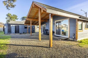 A modern house with a covered porch, a garage, and a barbecue area. - Cozy Crabin - Pet Friendly, Trailer Hook Up, Boat parking, Bay Access (Waldport)