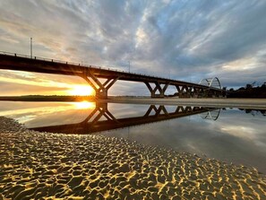 Eine Brücke über ruhigem Wasser, das Sonnenuntergang widerspiegelt.
