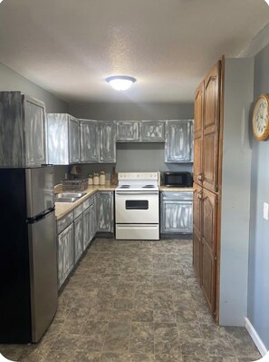 A compact kitchen with a refrigerator, stove, microwave, and wooden cabinets. - Cozy 1-bedroom house in wonderful Doniphan with AC (Doniphan)