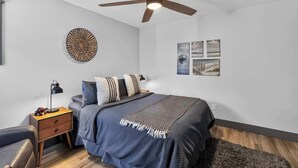 Une chambre à coucher avec un lit, une table de chevet, une lampe et des œuvres d’art murales.