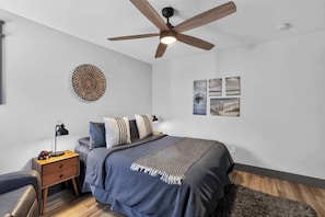 A bedroom with a bed, bedside table, lamp, and wall art. - Dory Coastal Paradise - walk to Cape Kiwanda (Pacific City)