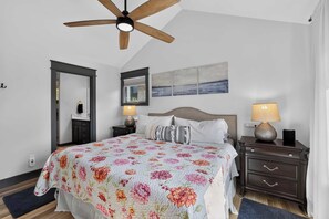 A bedroom with a bed, a ceiling fan, a nightstand with a lamp, a dresser, and artwork on the wall. - Dory Coastal Paradise - walk to Cape Kiwanda (Pacific City)