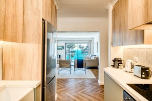 Una cocina moderna con armarios de madera, un refrigerador de acero inoxidable y un comedor con vistas al exterior.