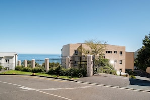 Ein geschlossenes Wohngebiet mit freiem Blick auf das Meer, einer gepflasterten Straße und einem Gebäude mit Backsteinfassade.