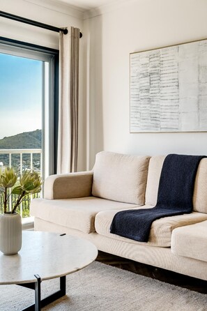 Ein modernes Wohnzimmer mit einer Couch, einem Couchtisch und Blick ins Freie.