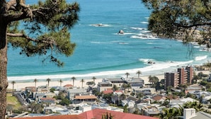 A coastal town with a beach, residential buildings, and a view of the ocean. - Camps Bay 2 Bed With Sea Views Shoreline Views (Cape Town)