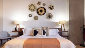 Ett hotellrum med en stor säng, två sängbord, en stol och dekorationer på väggarna.