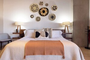 A hotel room with a large bed, two bedside tables, a chair, and wall decor. - Cómodo y moderno en col. Amerciana Mariachiloft (Guadalajara)