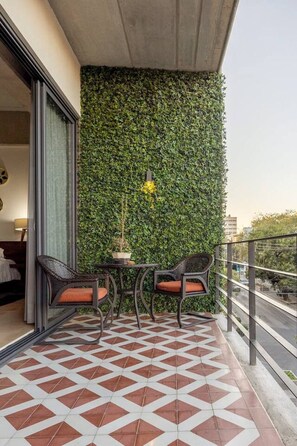 A balcony with a patterned floor, two chairs, a small table, and a green wall. - Cómodo y moderno en col. Amerciana Mariachiloft (Guadalajara)