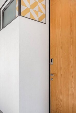 A room with a wooden door, a white wall, and a geometric patterned wall decoration. - Cómodo y moderno en col. Amerciana Mariachiloft (Guadalajara)