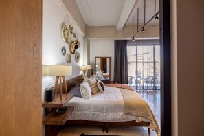 Une chambre d’hôtel avec un grand lit, des lampes de chevet, une table de chevet en bois et une vue sur l’extérieur grâce à une grande fenêtre.