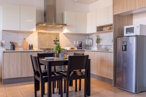 A modern kitchen with a central island, a built-in stove, and a stainless steel refrigerator. - Cómodo y moderno en col. Amerciana Mariachiloft (Guadalajara)