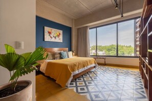 A hotel room with a bed, a large window, a plant, and a geometric patterned floor. - Tequiloft arte y esencia Col.Americana@grupo.xingo (Guadalajara)