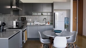 Una cucina moderna con mobili grigi, forno a incasso, microonde e dispenser d'acqua.