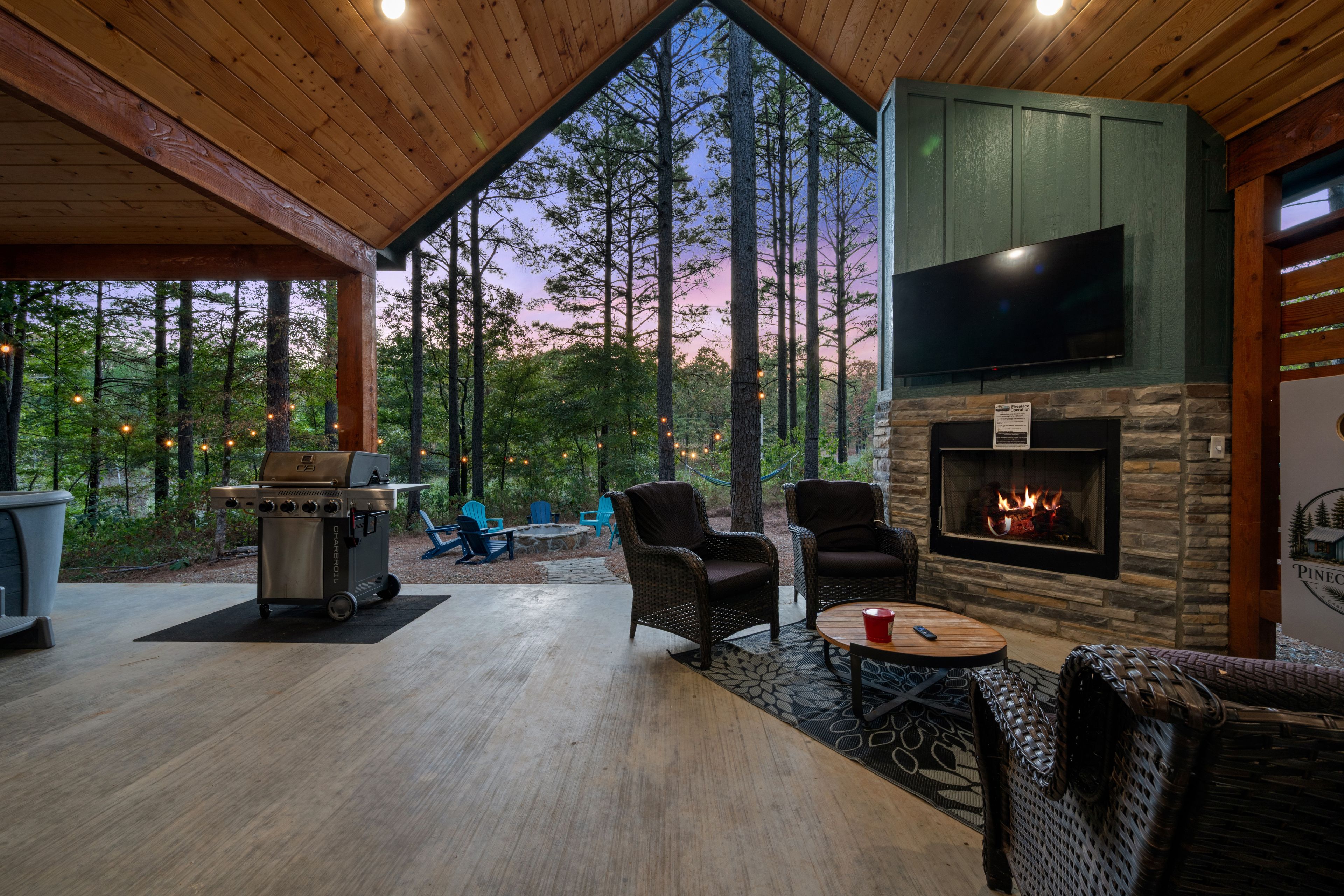 A covered outdoor area with a fireplace, seating, and a grill.