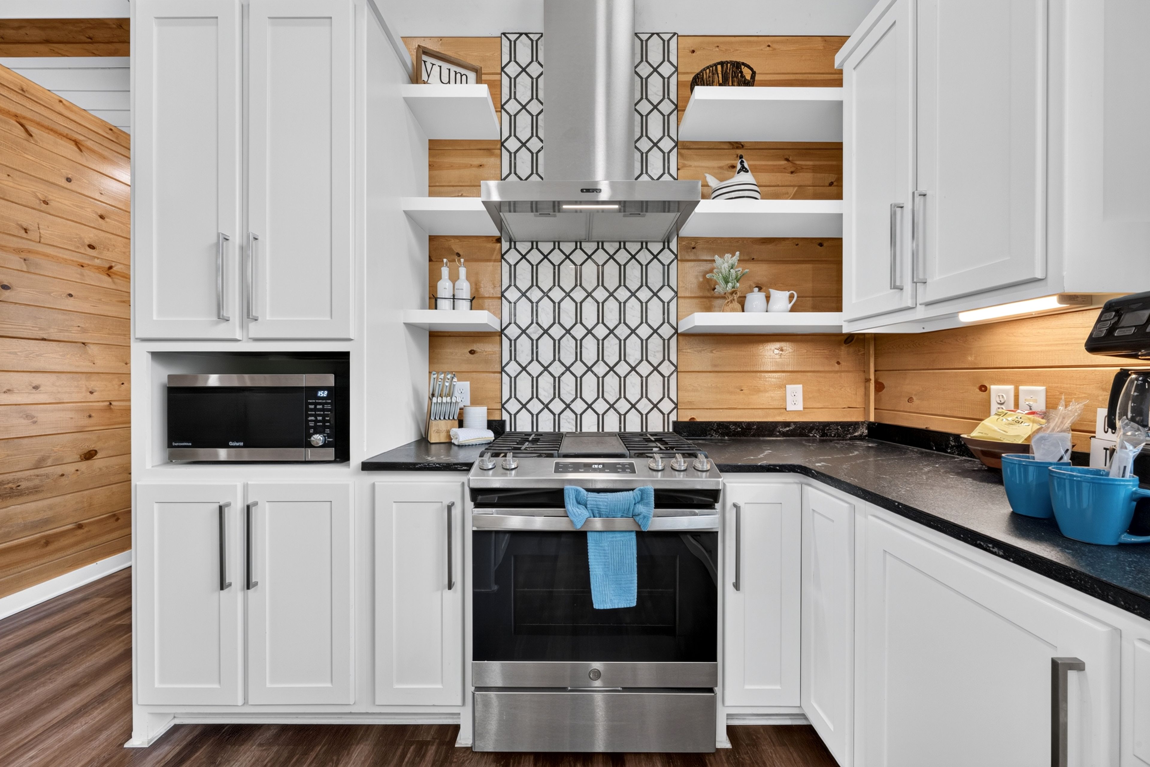 Une cuisine moderne avec des meubles blancs, une cuisinière en acier inoxydable et un four à micro-ondes.