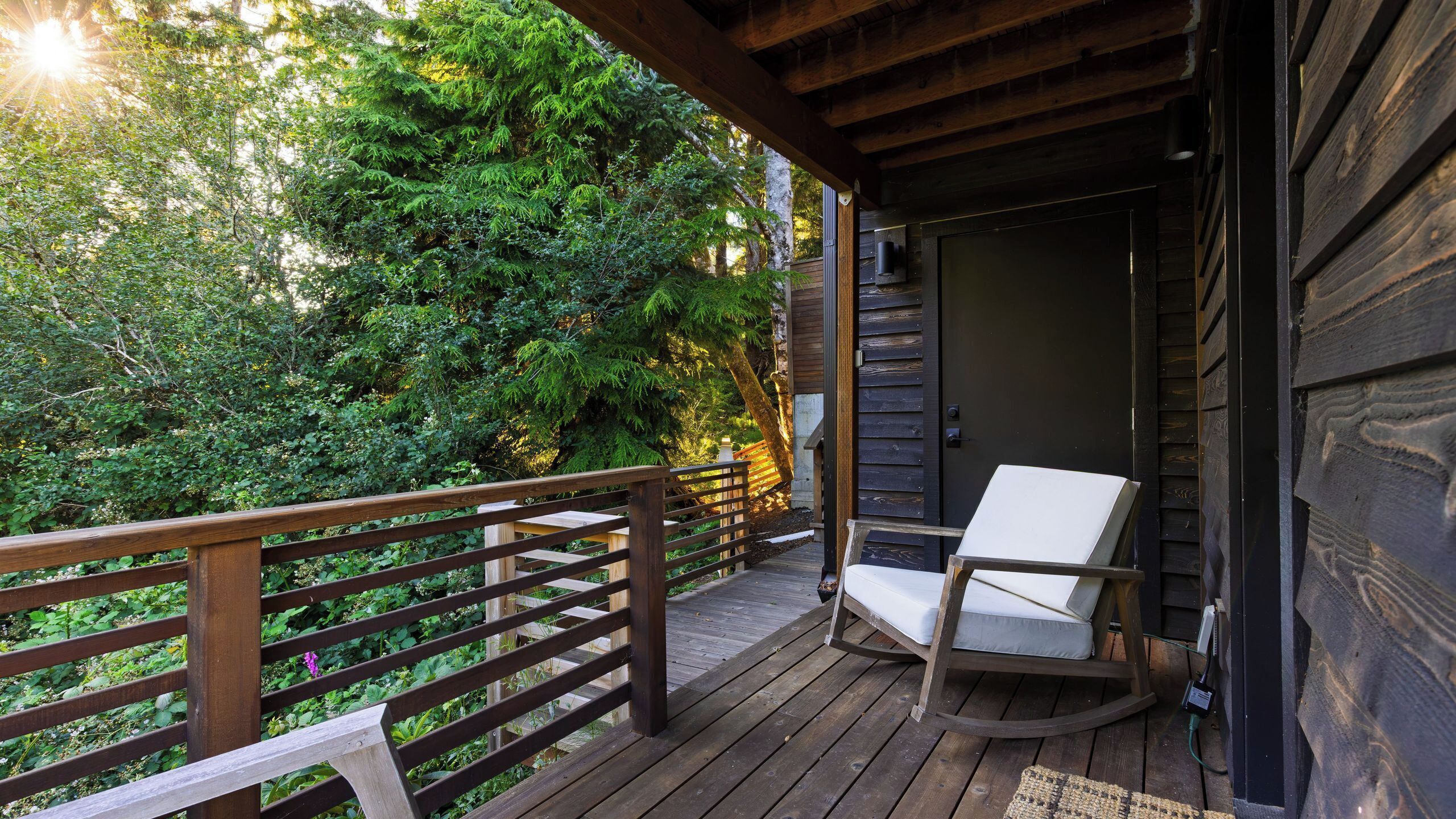 Une terrasse en bois avec une chaise berçante et une rambarde en bois.