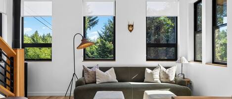 A modern living room with a sofa, a lamp, and a decorative wall piece.