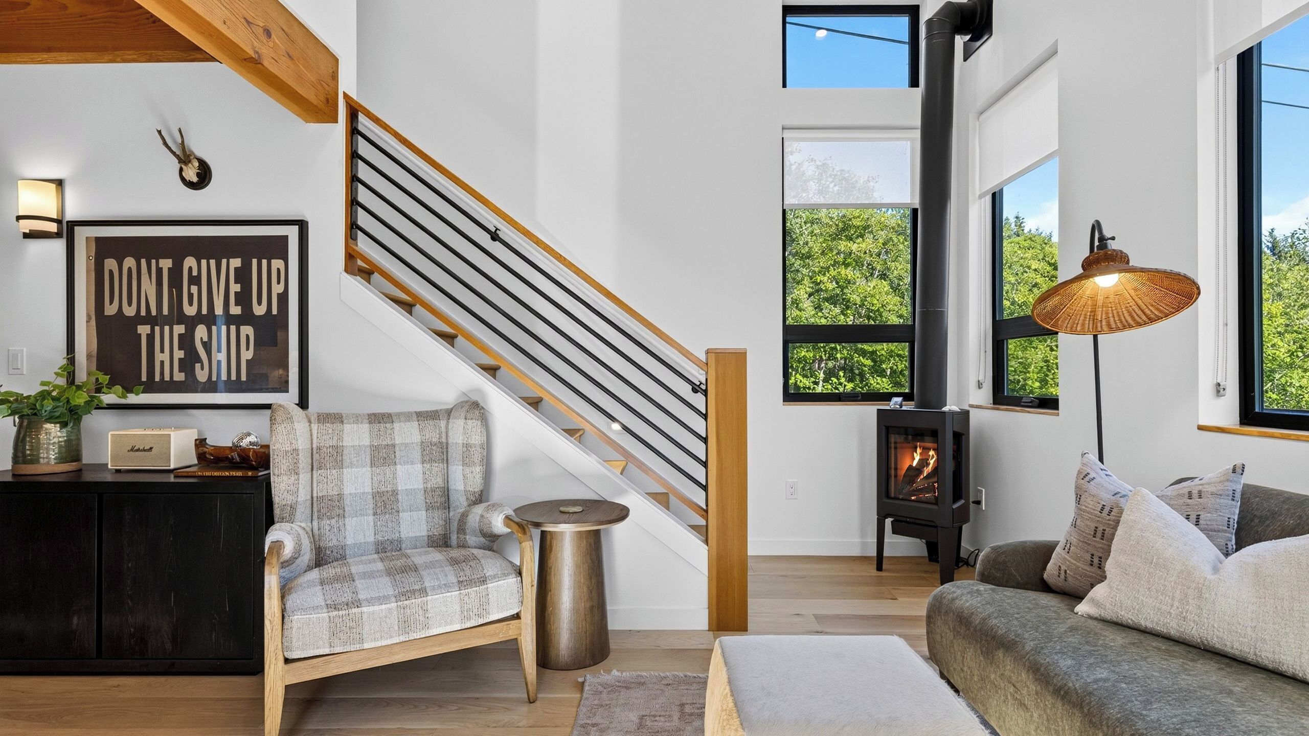 A modern living room with a staircase, a fireplace, and a motivational quote on the wall.