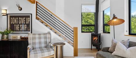 A modern living room with a staircase, a fireplace, and a motivational quote on the wall.