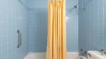 Un baño con bañera, cortina de ducha amarilla y barra de apoyo.
