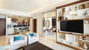 Ein modernes Wohnzimmer mit Fernseher, Sofas, einem Couchtisch und einem Essbereich mit Stühlen und Tisch.