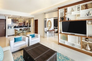 A modern living room with a television, sofas, a coffee table, and a dining area with chairs and a table. - 2-bedroom condo in superb Cabo San Lucas with AC and gym (Cabo San Lucas)