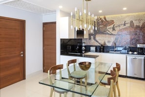 A modern kitchen with a glass dining table, wooden chairs, and a mosaic backsplash. - 2-bedroom condo in superb Cabo San Lucas with AC and gym (Cabo San Lucas)