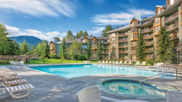 Ein Resort mit Schwimmbad, Liegestühlen und einer Bergkulisse.