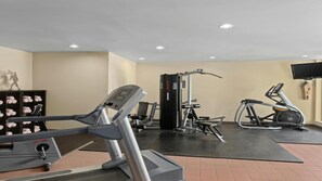 Une salle de sport équipée de tapis de course, d’appareils de musculation et d’un vélo elliptique.