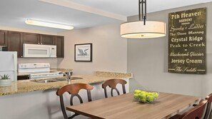 Eine moderne Küche mit Granit-Arbeitsplatten, Edelstahlgeräten und einem Essbereich mit Holztisch und Stühlen.