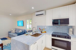 A modern kitchen with a central island, built-in oven, and white cabinetry. - Lost Shaker by the Sea (Lauderdale-by-the-Sea)