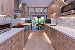 A modern kitchen with wooden cabinets, a Bosch microwave, and a dining area with a view. - Stylish Spanish townhome w/ mountain views, pool & spa in South Palm Springs (Palm Springs)