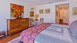 Un dormitorio con cama, cómoda, sillas y obras de arte en las paredes.