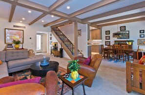 A spacious living area with a sofa, armchairs, a coffee table, and a staircase leading to a kitchen. - Stylish Spanish townhome w/ mountain views, pool & spa in South Palm Springs (Palm Springs)