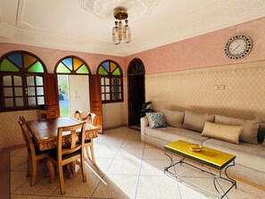 A room with a dining table, chairs, a sofa, and a patterned wall. - Villa Targante, Essaouira (Essaouira)