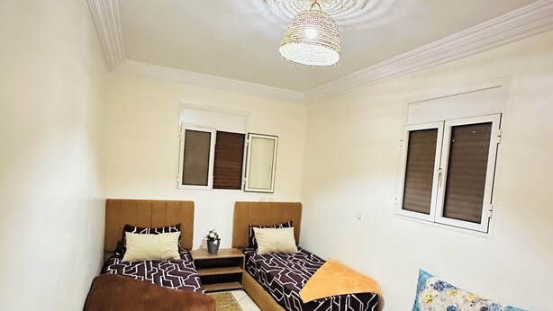 A room with two beds, a sofa, a chandelier, and a window with shutters. - Villa Targante, Essaouira (Essaouira)