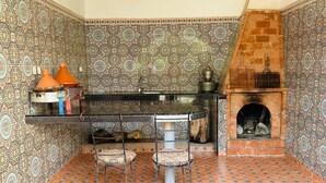 A kitchen with patterned tiles, a brick oven, and a dining area with chairs. - Villa Targante, Essaouira (Essaouira)