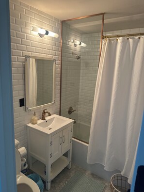 A bathroom with a white sink, mirror, and shower.