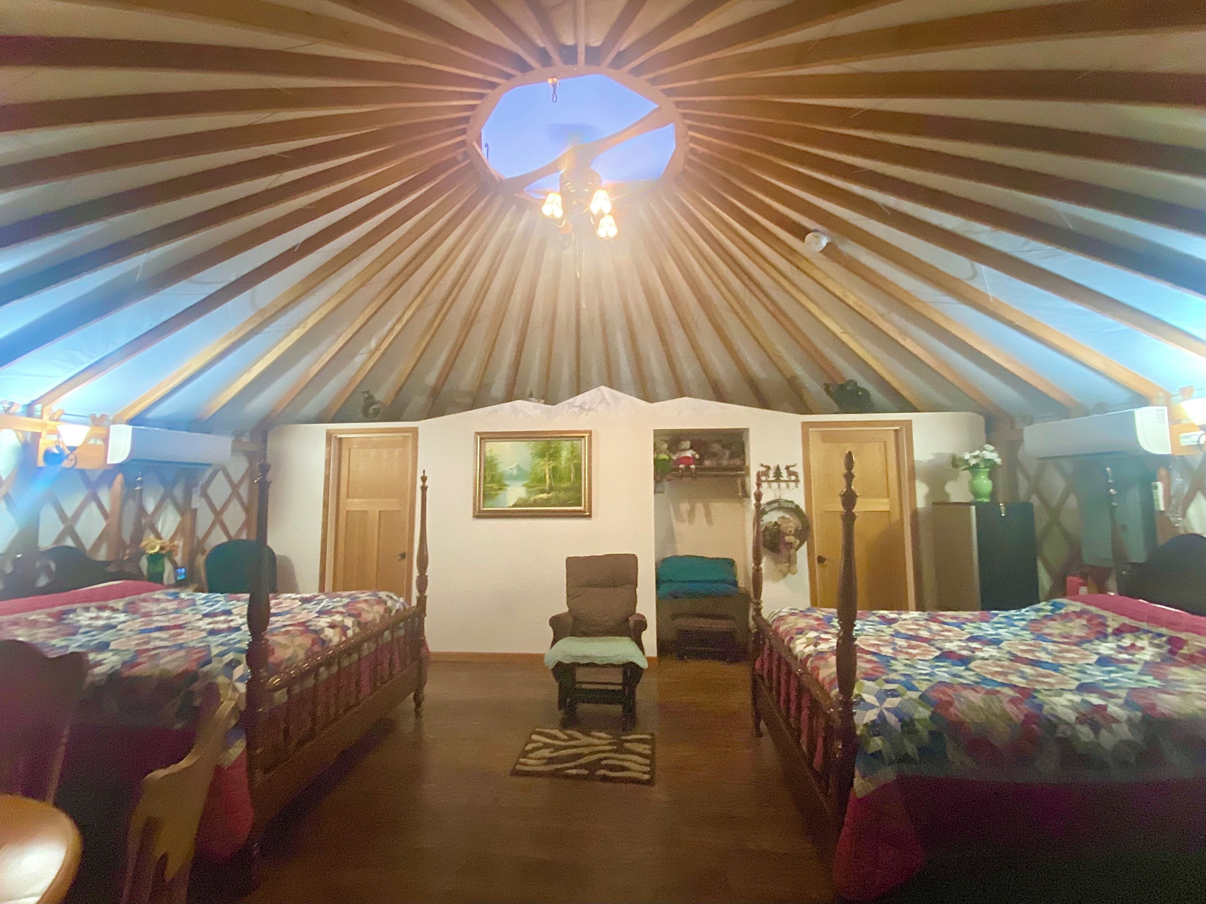 A tent-style room with two beds, a chair, and a small table.