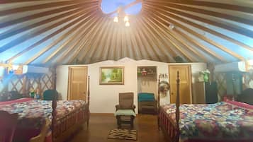 A tent-style room with two beds, a chair, and a small table.