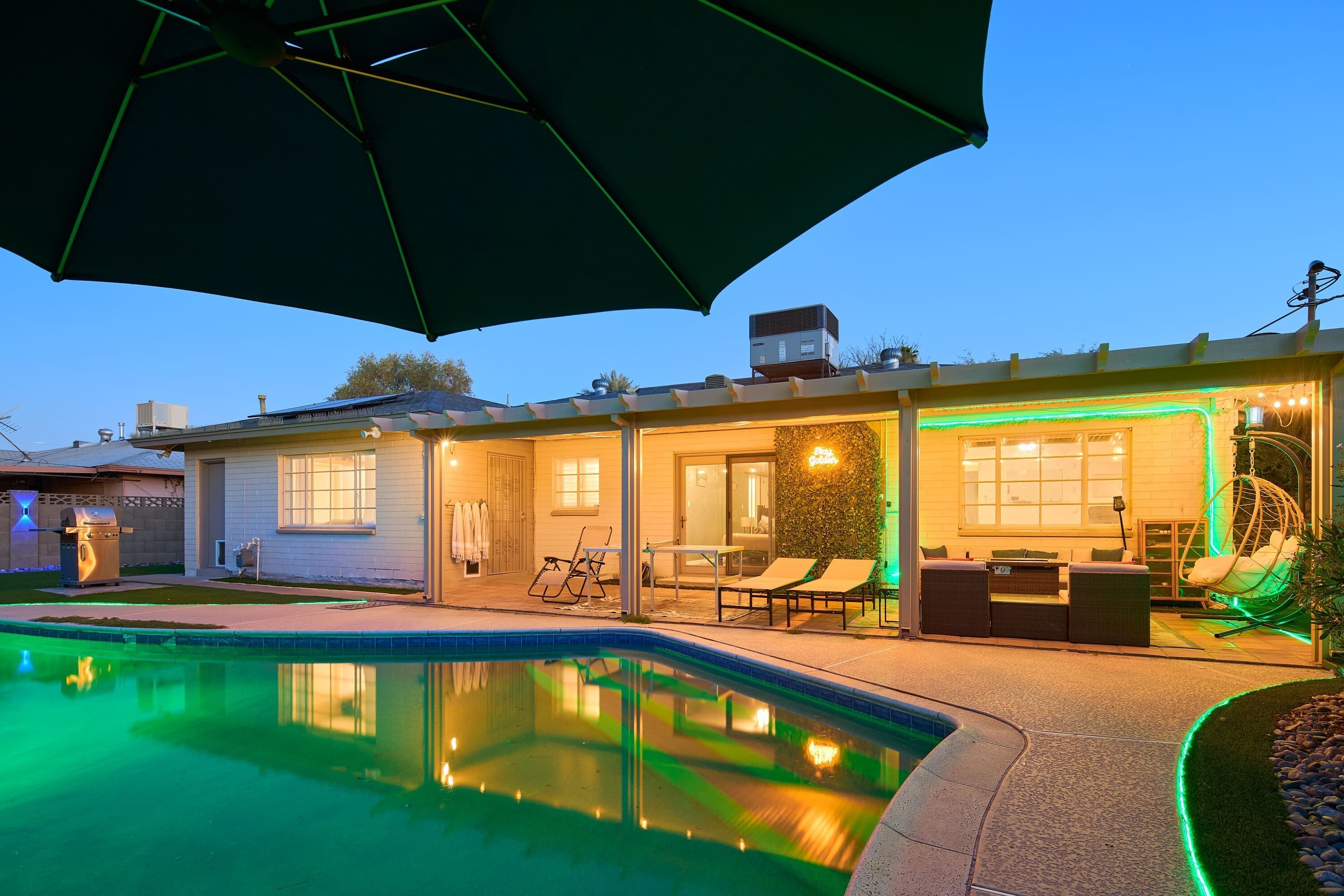 A residential property with a swimming pool, outdoor seating, and a covered patio area.