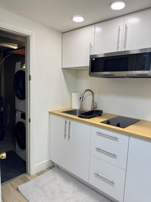 A modern kitchen with a built-in microwave, sink, and stainless steel appliances. - Renovated and private garden apartment near UofU. (Salt Lake City)