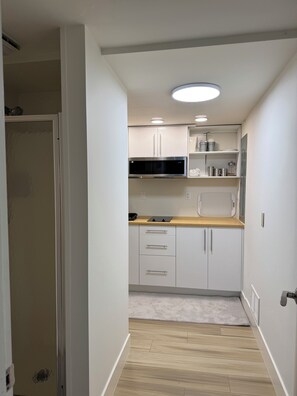 A modern kitchen with white cabinets, a microwave, and a built-in oven. - Renovated and private garden apartment near UofU. (Salt Lake City)