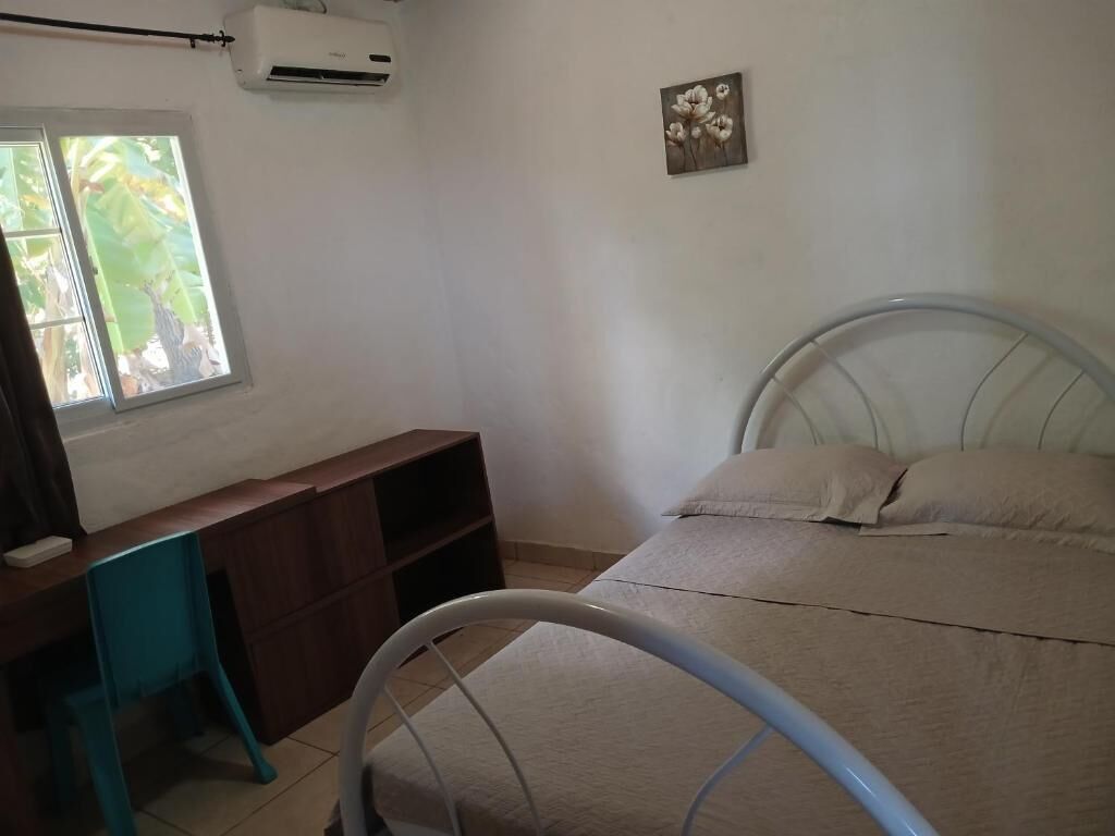 Un dormitorio con cama, escritorio y ventana.