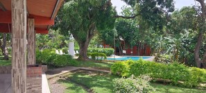 Un área de piscina con una estructura de ladrillo, rodeada de abundante vegetación y árboles.