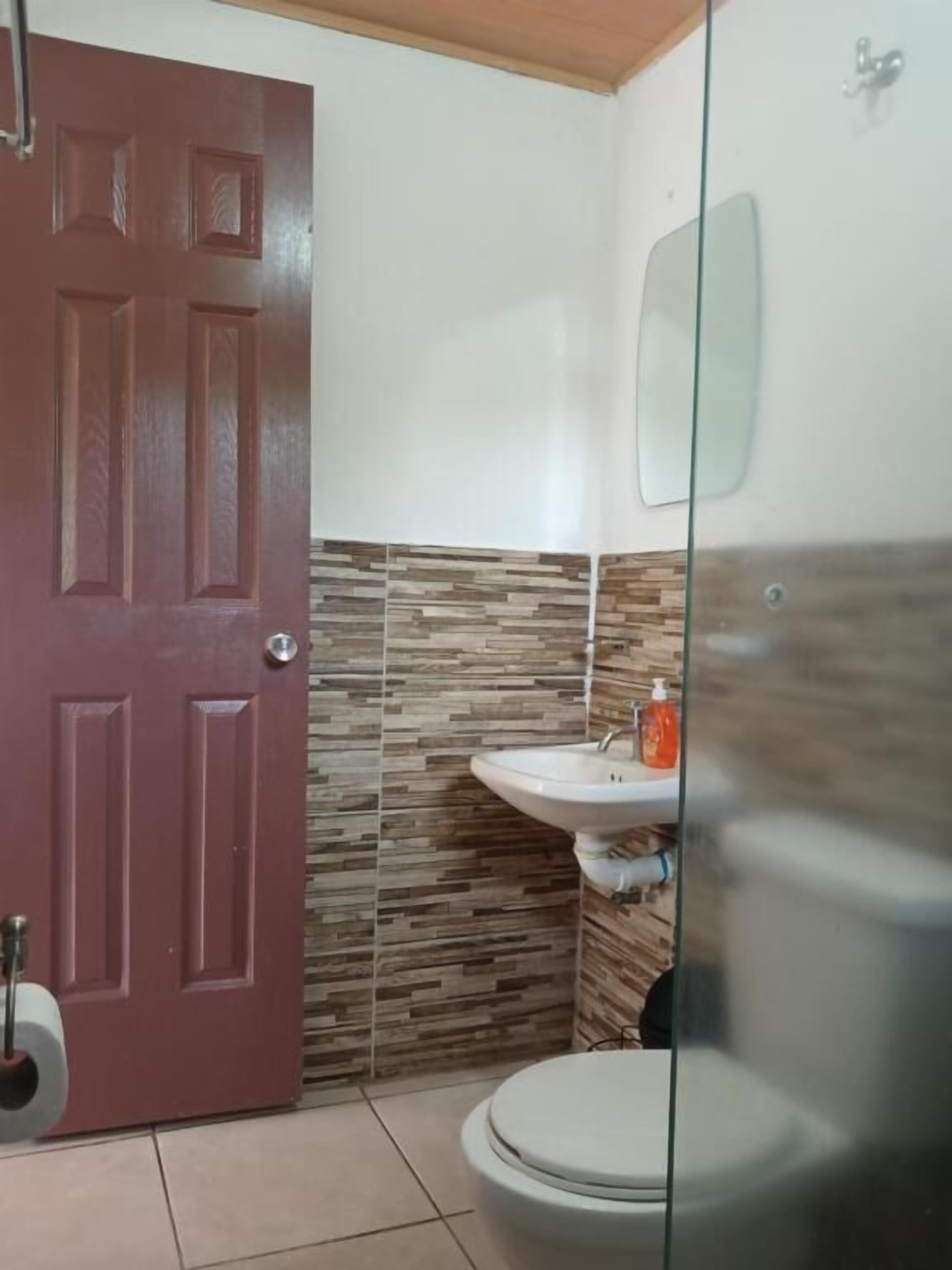 A bathroom with a toilet, sink, and a glass shower enclosure.