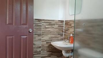 A bathroom with a toilet, sink, and a glass shower enclosure.