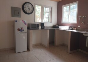 A kitchen with a refrigerator, microwave, and coffee maker.